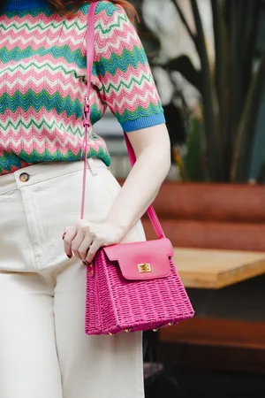 Amici Ollie Rattan Crossbody Tasche in Pink.